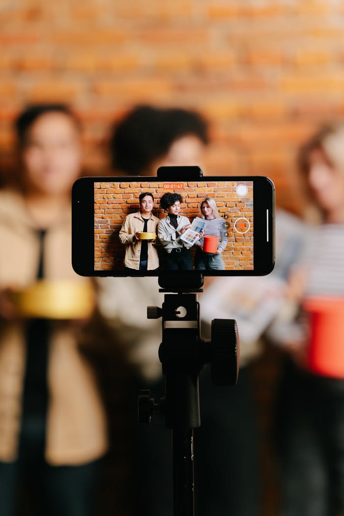 Diverse group of friends filming a video with a smartphone on a tripod indoors.